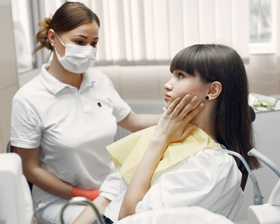 Dentista atendiendo a una paciente en su consultorio
