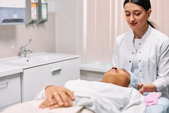 Cosmetóloga preparando un tratamiento facial a una paciente en su cabina