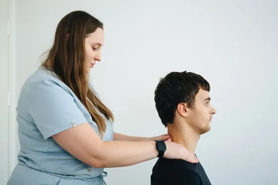 Fisioterapeuta revisando el cuello y el hombro de un paciente
